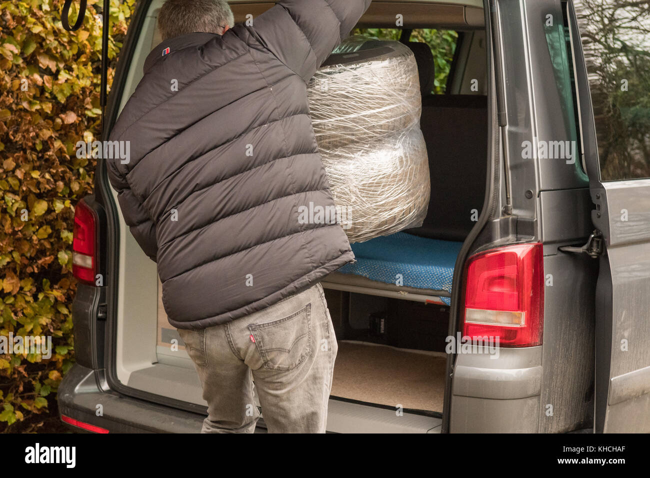 Mann, der Winterreifen nimmt, um auf das winterfertige Fahrzeug montiert zu werden - Schottland, Großbritannien Stockfoto