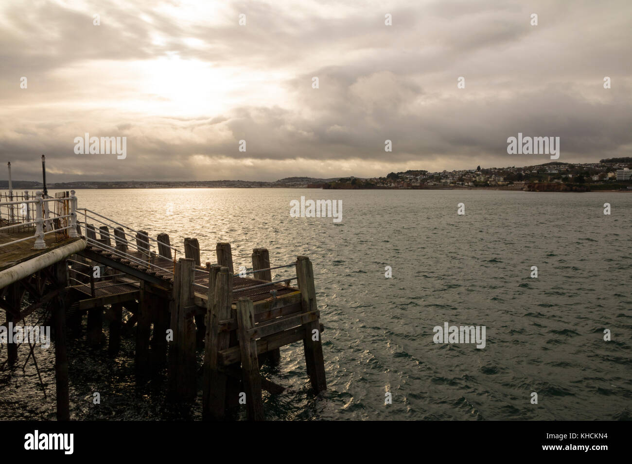 Sonnenuntergang über Torbay von Torquay Pier mit einem Bootssteg im Vordergrund. Dunkle Wolken mit Sturm nähert. Stockfoto