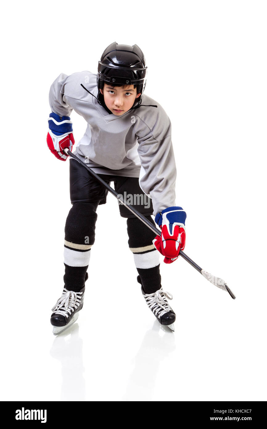 Portrait von Junior Ice Hockey Player auf dem Alarm mit voller Ausrüstung und einheitliche für einen Schuß mit einem Puck posieren. auf weißem Hintergrund. Stockfoto