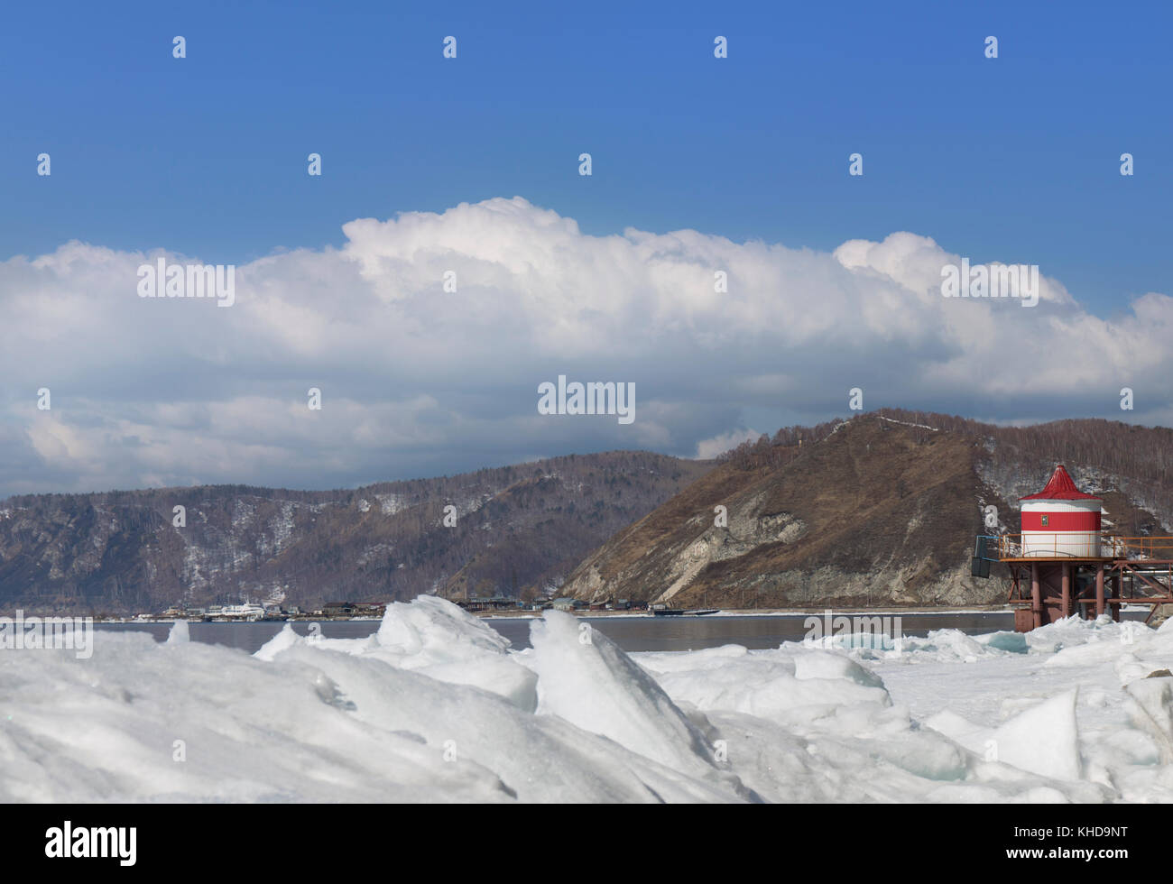 Eis Hängematten auf dem See Baikal. Sibirien winter Querformat mit rot-weissen Leuchtturm. schneebedeckte Eis des Sees. große Risse im Eis. Weiße Wolken am blauen Himmel Stockfoto