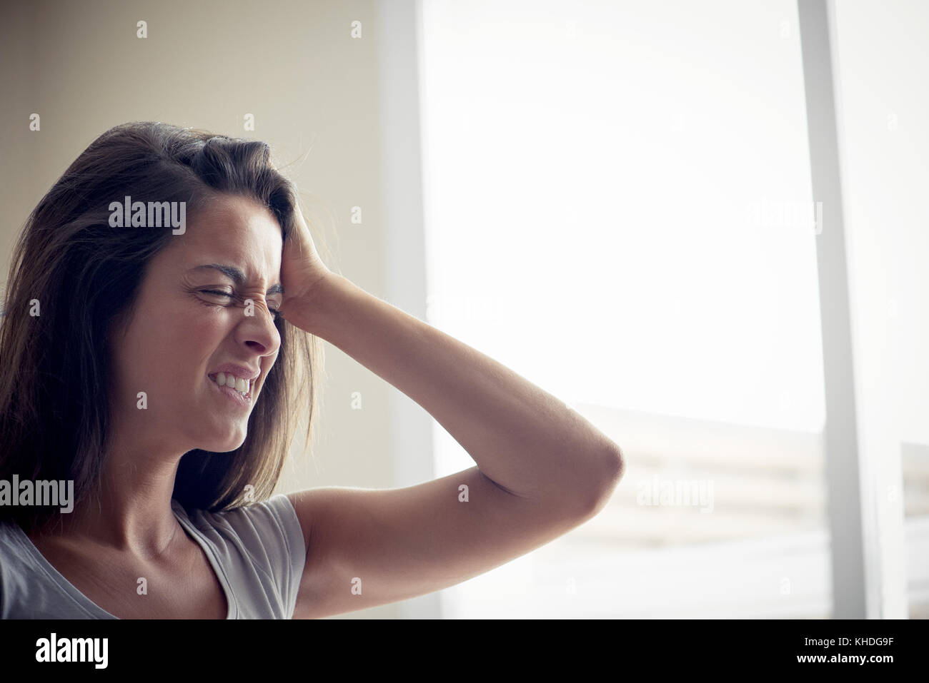 Junge Frau mit einer Hand auf die Stirn, die Augen geschlossen Stockfoto