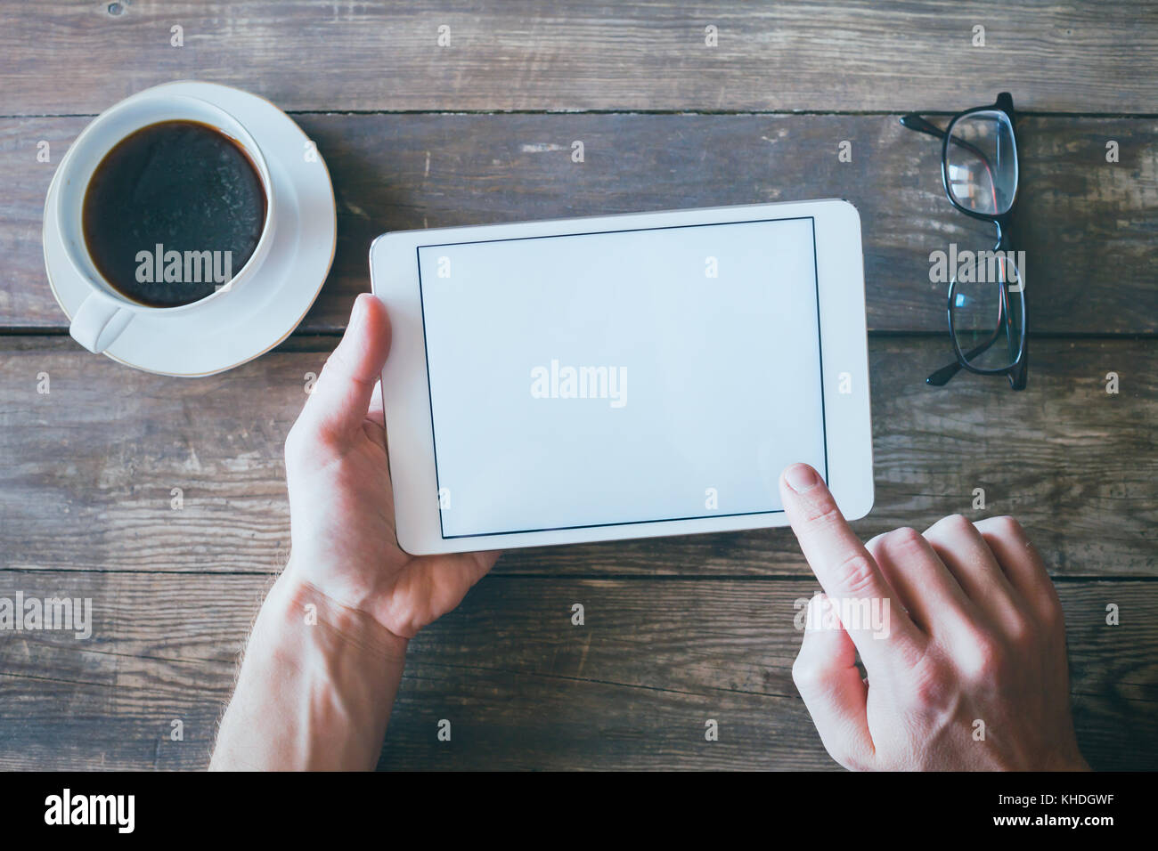 Hände halten digitale Tablet Computer mit weißen Leeren leeren Bildschirm auf Holz Schreibtisch Hintergrund Stockfoto