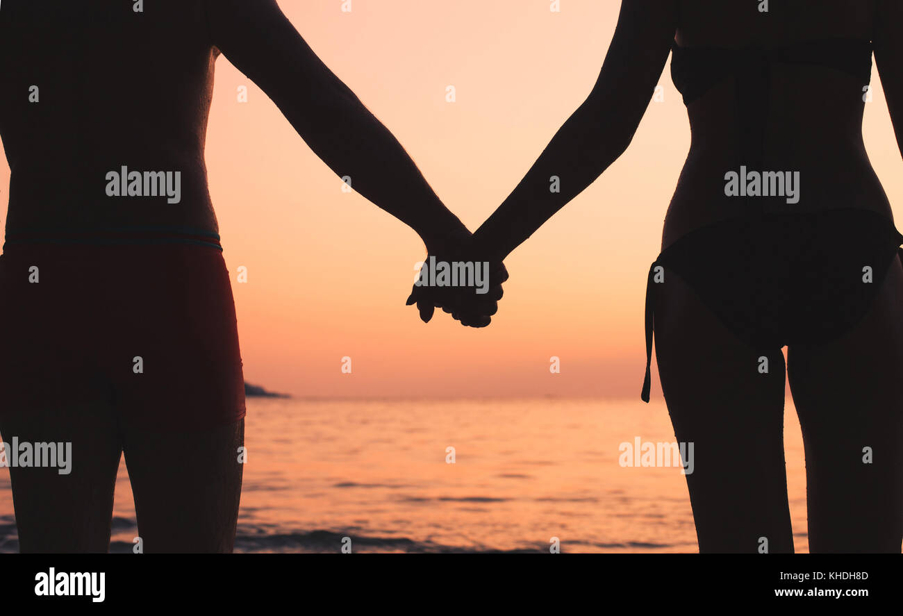 Romantische Reisen, Paar am Strand, Silhouette des Mannes und der Frau, Hände halten bei Sonnenuntergang Stockfoto