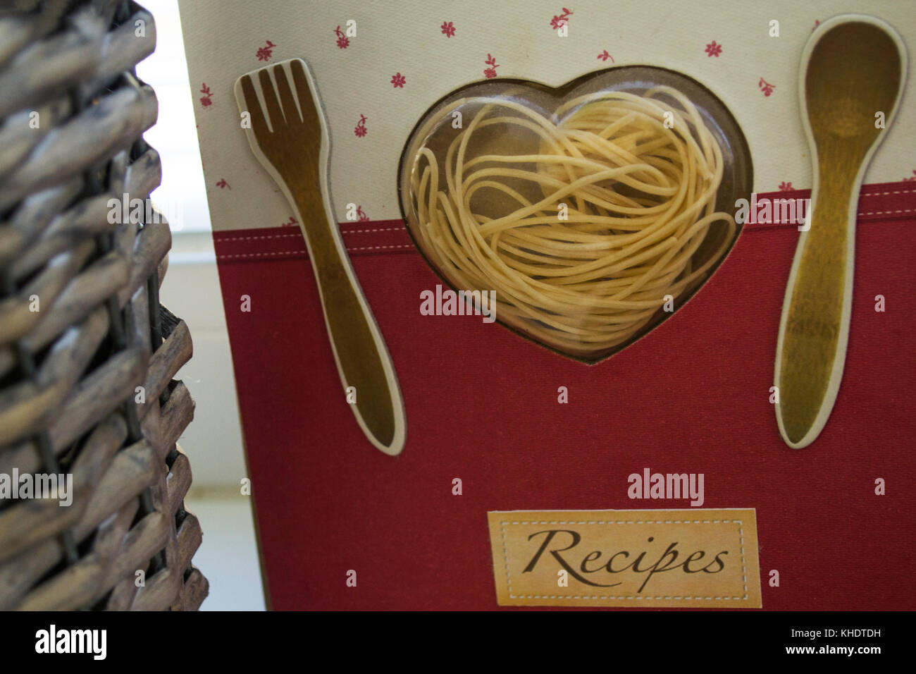 Nahaufnahme von einem schönen Rezept Notebook mit einem transparenten Herz voll von Pasta und zwei Besteck Stücke - ein Löffel und eine Gabel eingerichtet Stockfoto