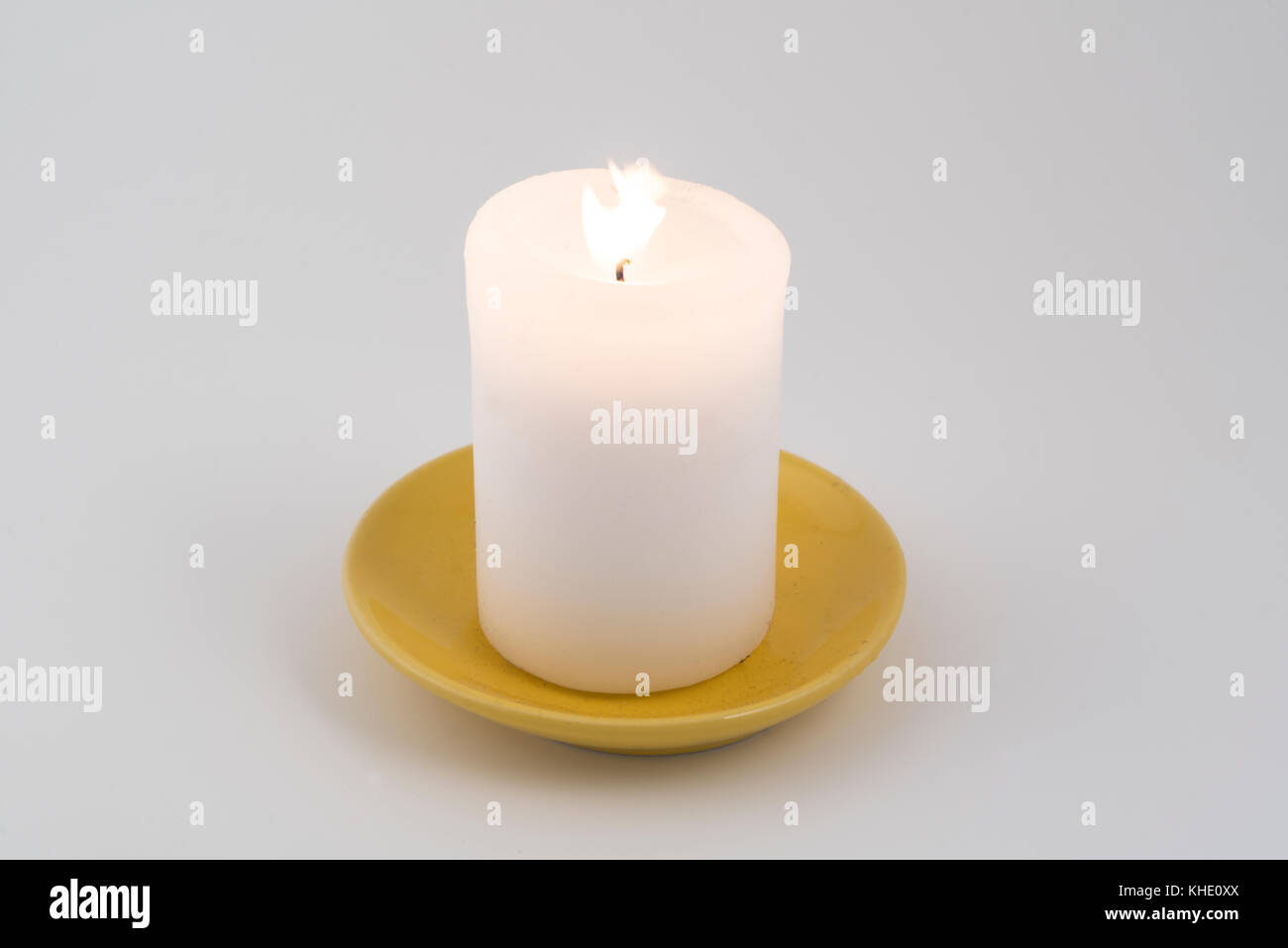 Eine weiße Kerze leuchtet auf weißem Hintergrund Stockfoto