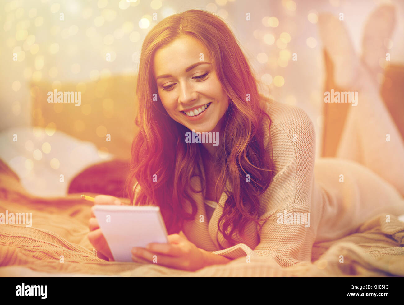 glückliche junge Frau mit Notebook im Bett zu Hause Stockfoto