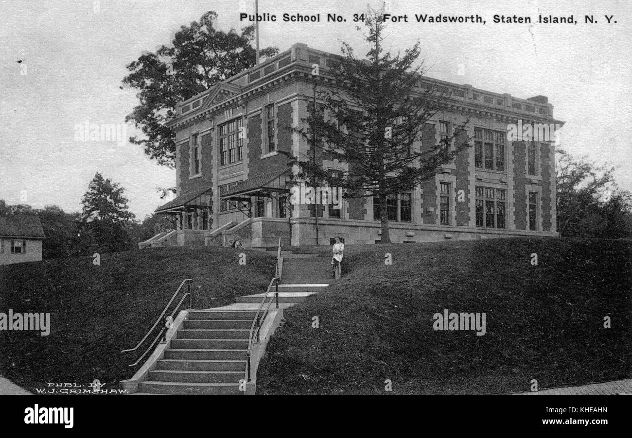 Eine Postkarte von einem Foto der öffentlichen Schule Nr. 34 in Fort Wadsworth, das zweistöckige Steingebäude befindet sich auf dem Gipfel eines kleinen, grasbedeckten Anstiegs, eine Steintreppe mit Handläufen führt zum Gebäude, eine Person kann gesehen werden, wie sie auf der Treppe nebenbei posiert, State Island, New York, 1900. Aus der New York Public Library. Stockfoto