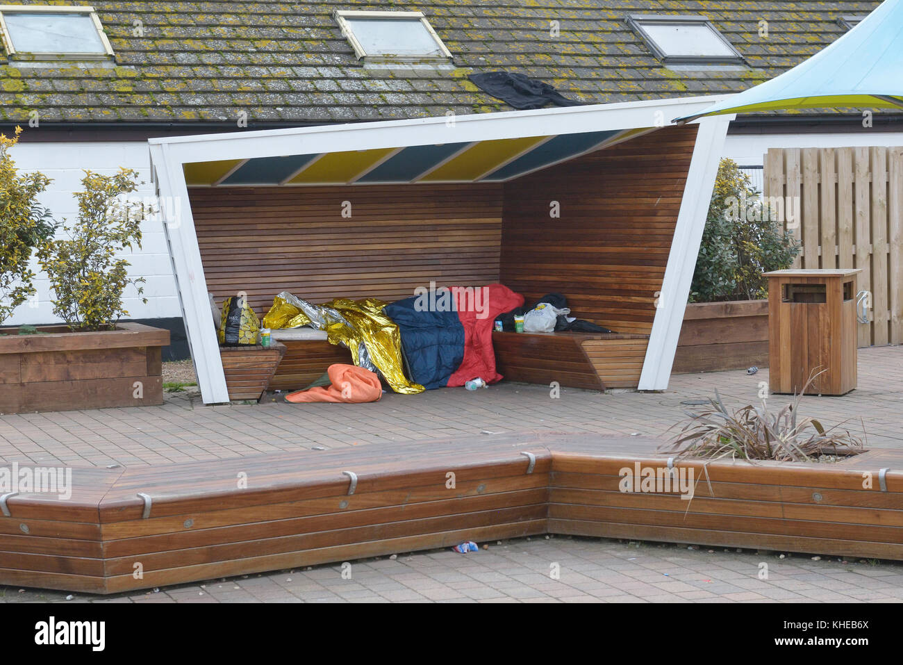 Ein obdachloser Mann schlafend auf einer Bank, Hastings, East Sussex, England, Großbritannien Stockfoto