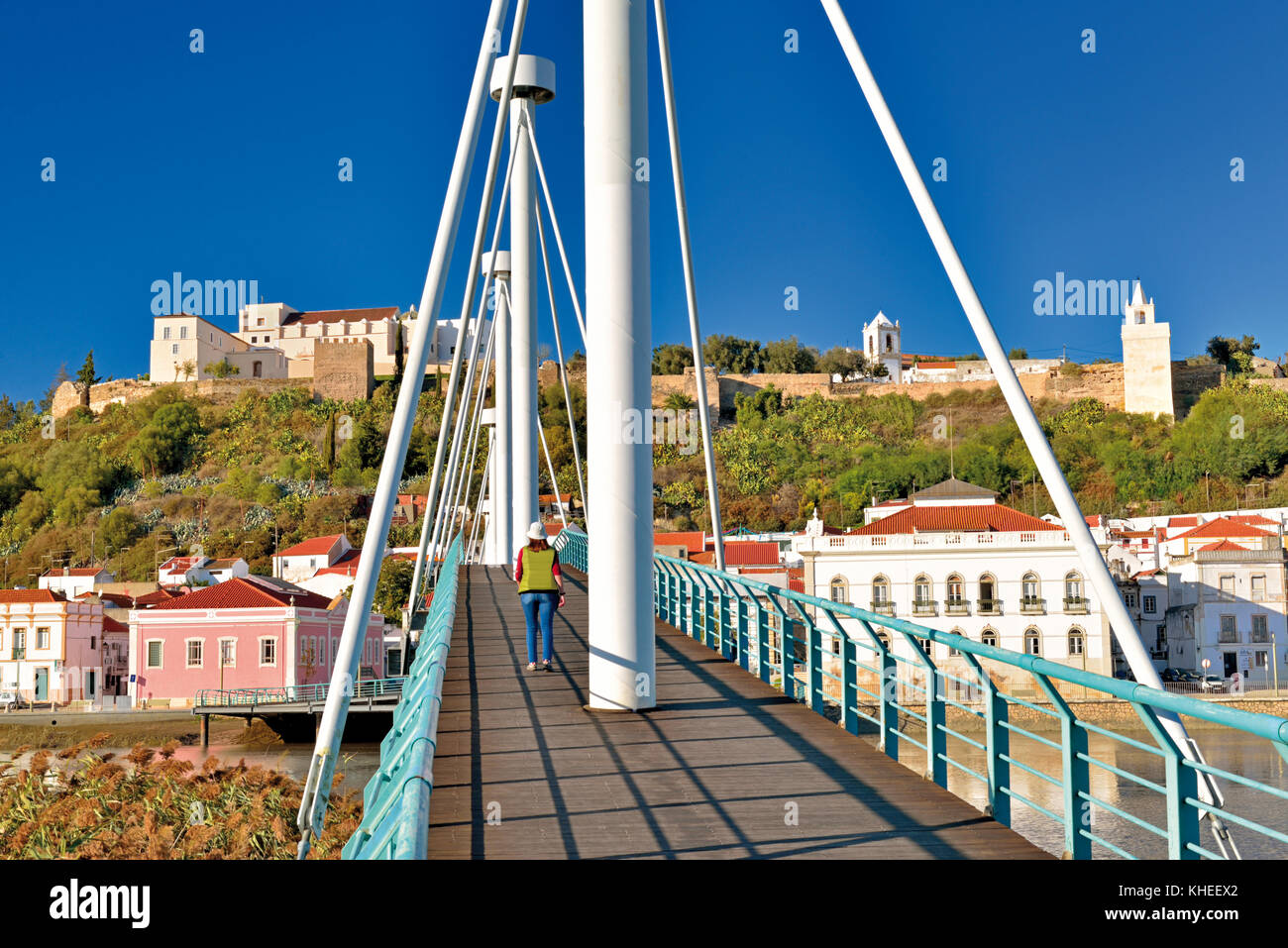 Frau überquert die moderne Fußgängerbrücke in Richtung des historischen Zentrums von Alcacer do Sal, Alentejo, Portugal Stockfoto