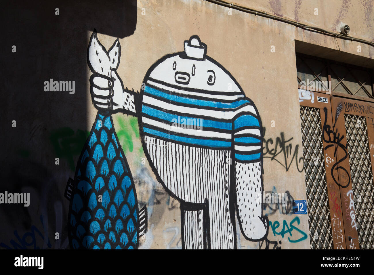 Graffiti eines Humanoiden, der einen Fisch in einer kleinen Straße in der Plaka-Region in Athen hält Stockfoto