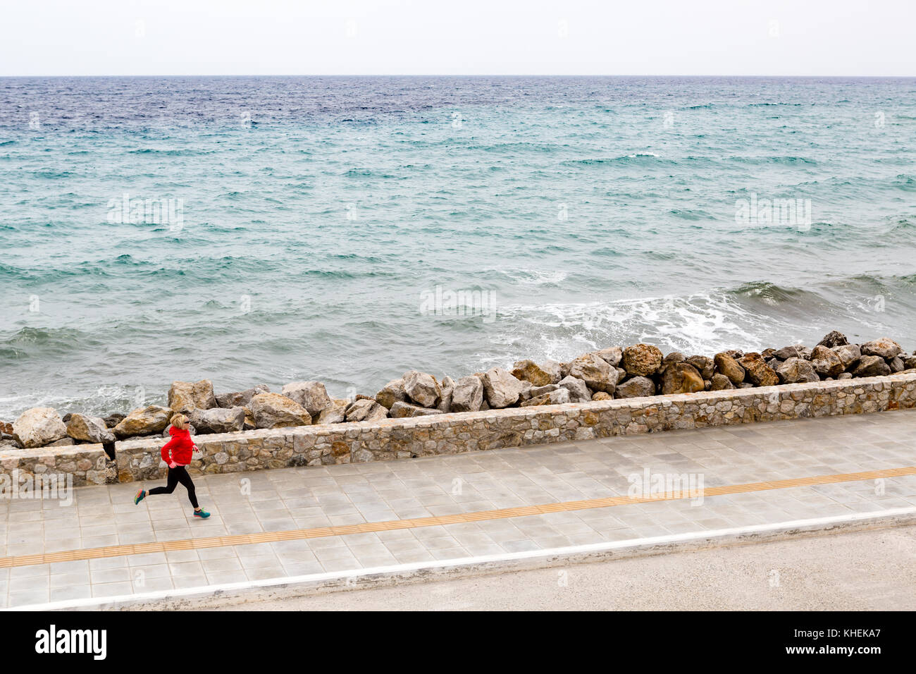 Frau joggt auf der Straße am Meer. Junge Athleten trainieren Laufen und Workout im Freien in der urbanen Szene. Sport- und Fitnesstraining inspira Stockfoto