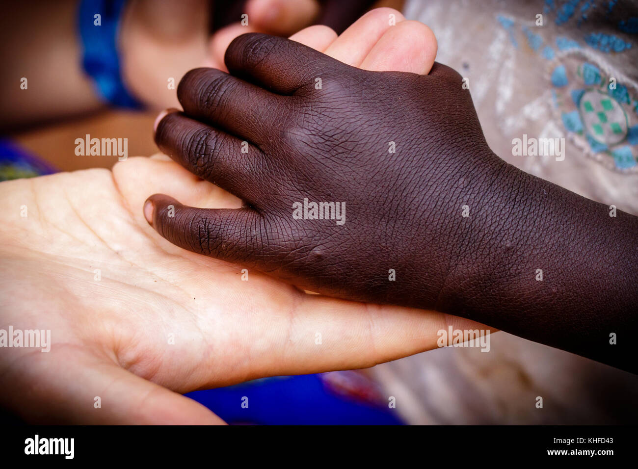 Ein weißes Mädchen bietet hier die Hand mit einem Mädchen während einer Nächstenliebe treffen im zentralen Uganda Stockfoto