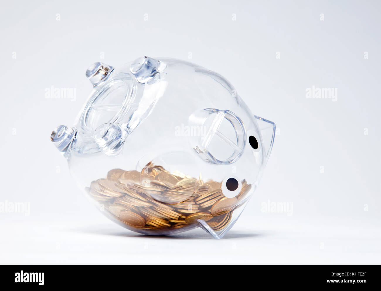 Transparentes Sparschwein mit goldenen Münzen auf den Kopf Stockfoto