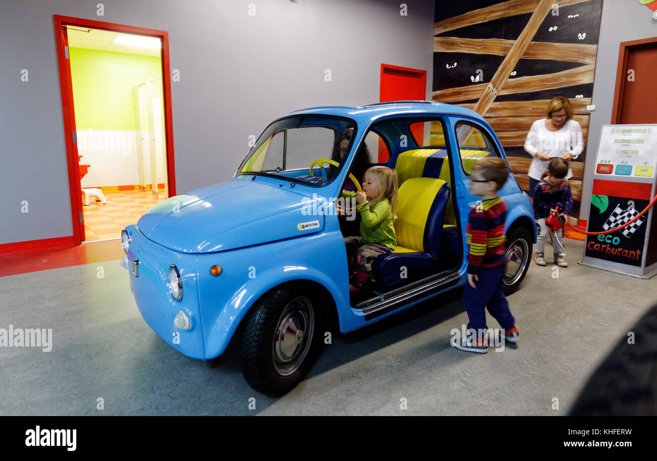Ein kleines Mädchen vorgibt, ein Fiat 500 im Musee D'Enfance indoor themed Play cenrtre in Laval, Quebec zu fahren Stockfoto
