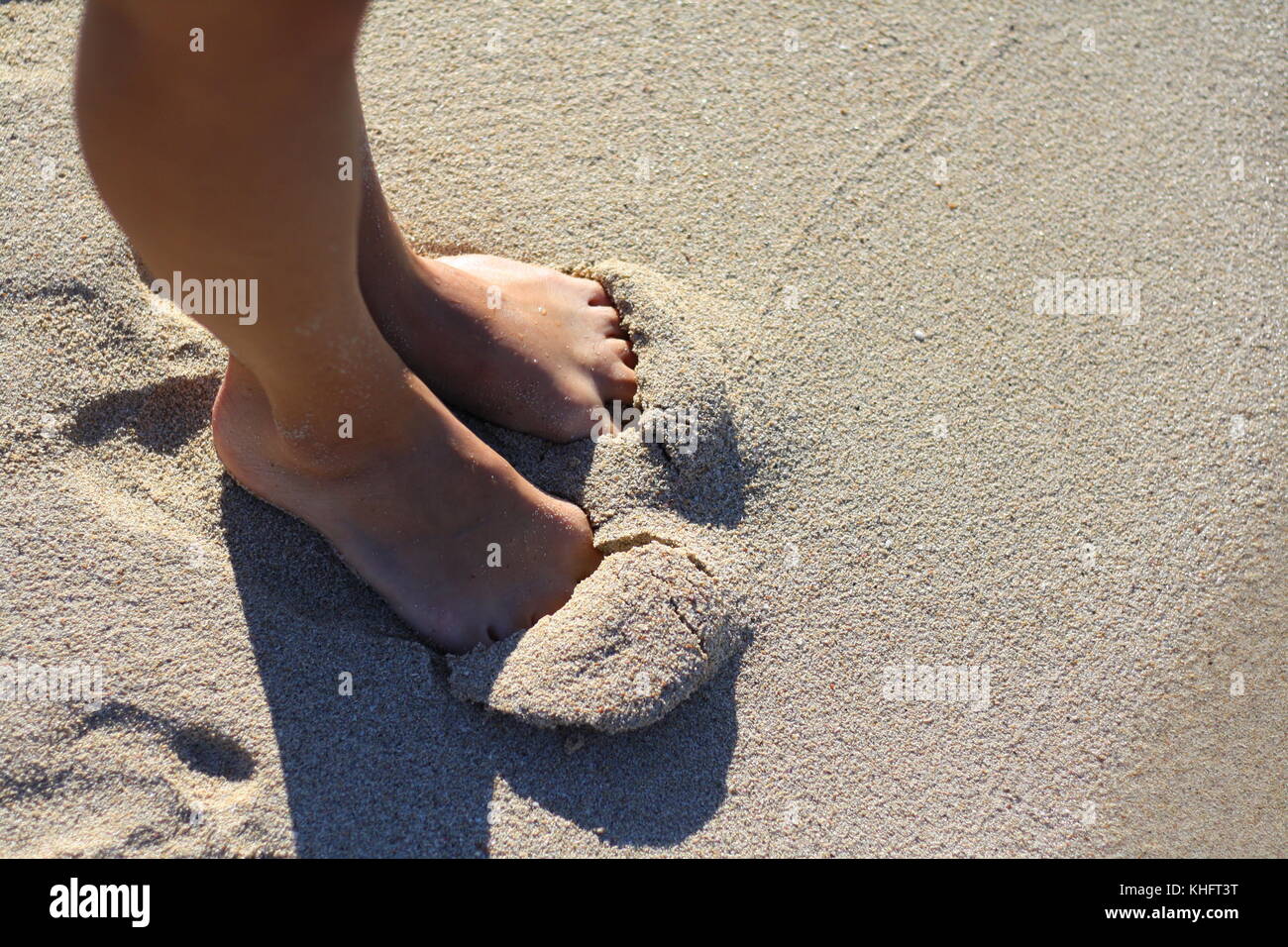 Eine Frau begräbt ihre Füße im Sand des Strandes. Stockfoto