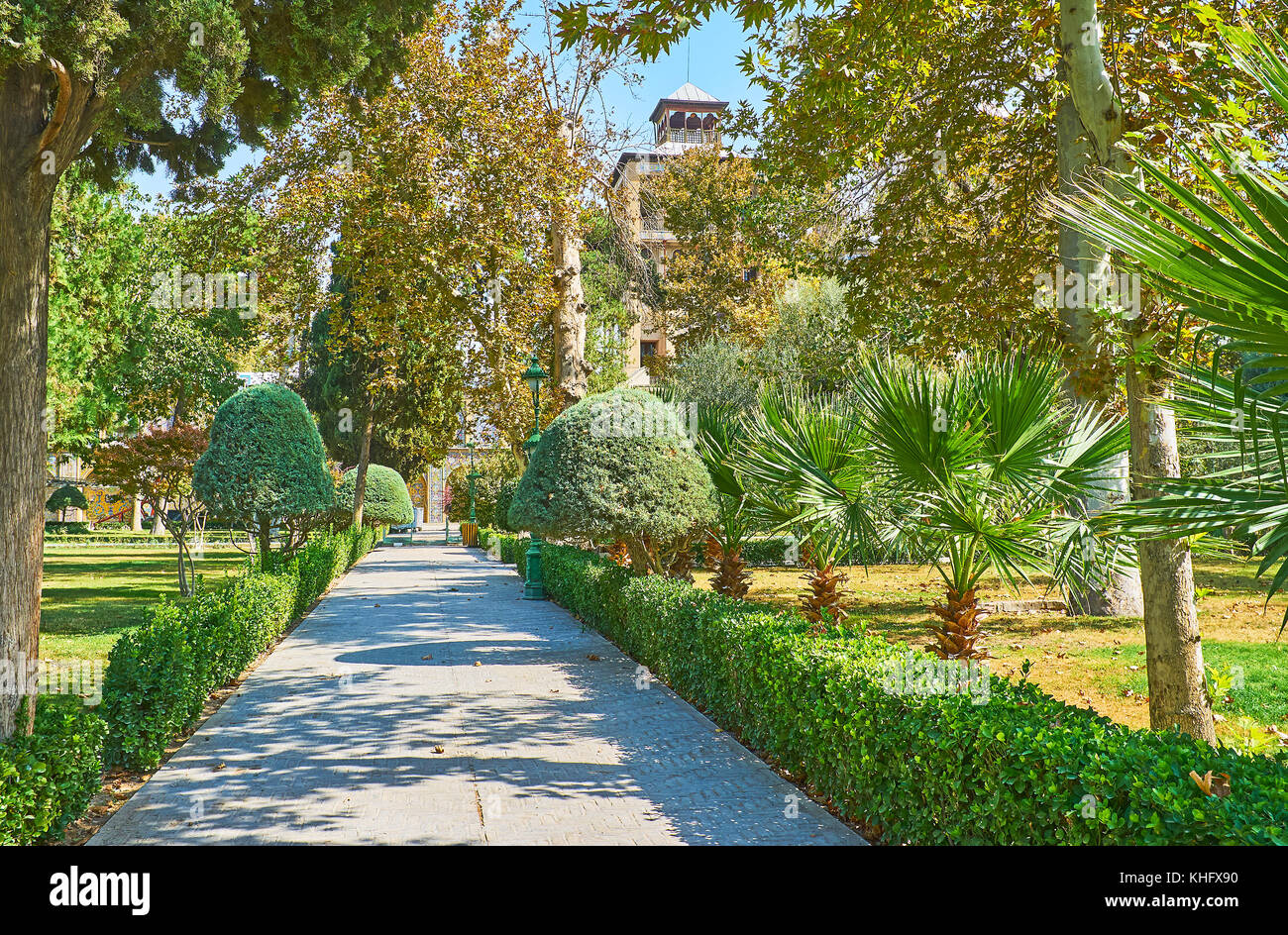 Die Gasse zwischen dem üppigen Grün der golestan Garten führt zu dem Gebäude der Sonne mit hohen Türmen, Teheran, Iran. Stockfoto