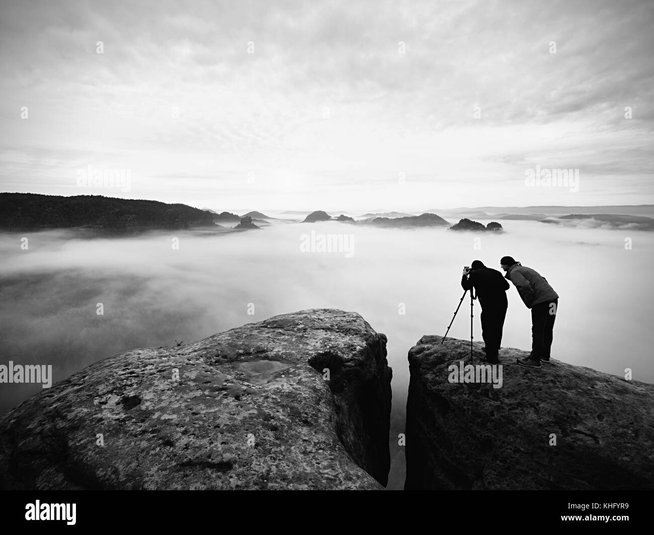 Zwei warmen Mantel Fotografen mit Stativ fotografieren der herbstlichen Landschaft unter Berg. regnerischen nebligen Tag in den Bergen mit bewölkter Himmel, kalt in Stockfoto