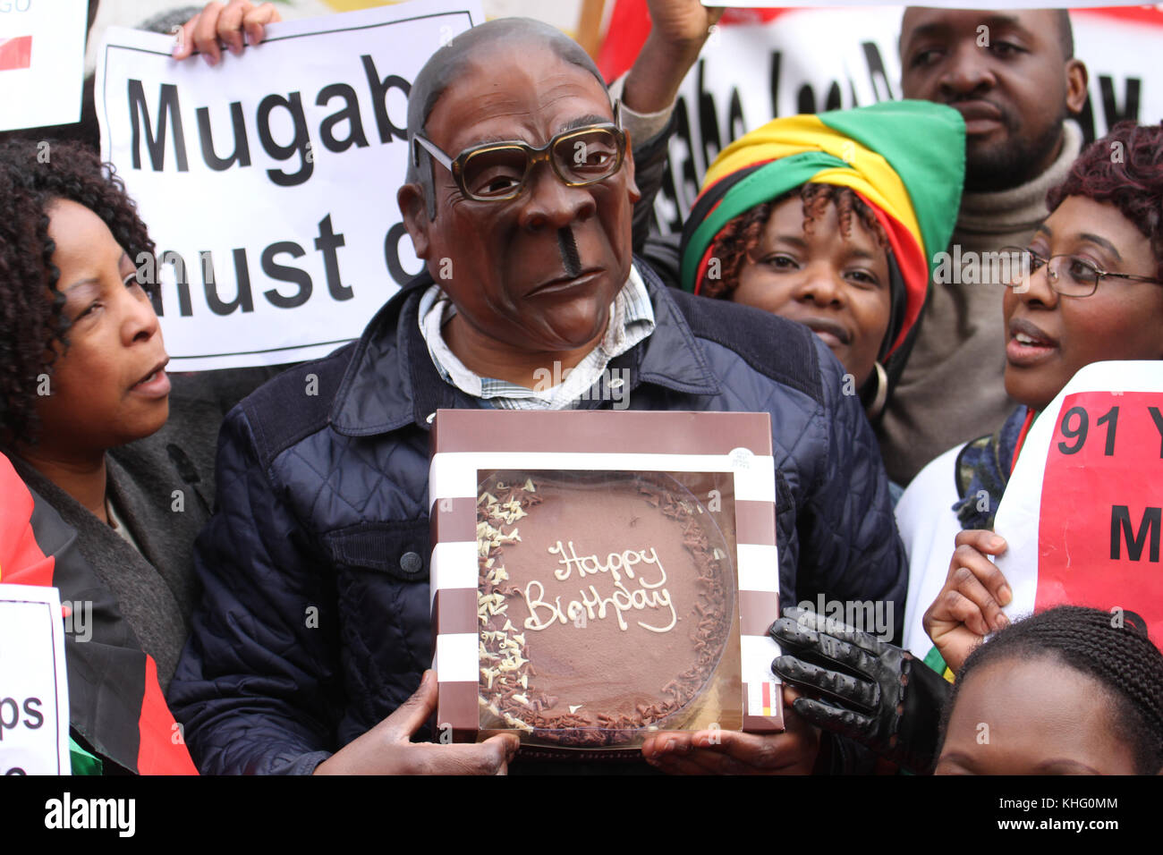London, Großbritannien. 21. Februar 2015: Ein mand mit Mugabe Maske halten einen Geburtstagskuchen außerhalb Simbabwe Haus in London am 91. Mugabes Geburtstag am 21. Robert Gabriel Mugabe ich Präsident von Simbabwe seit 1987, und hatte zuvor Simbabwe als Premierminister von 1980 bis 1987 geführt. Quelle: David Mbiyu/Alamy leben Nachrichten Stockfoto