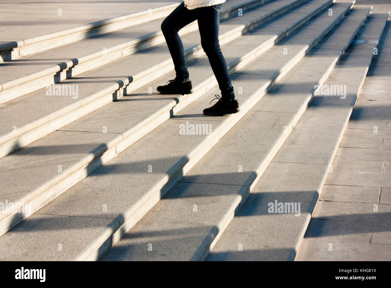 Ein junges Mädchen geht die Treppe hinauf in motion blur und Schatten der Menschen nach, die auf grossen öffentlichen Freibad Treppe Stockfoto