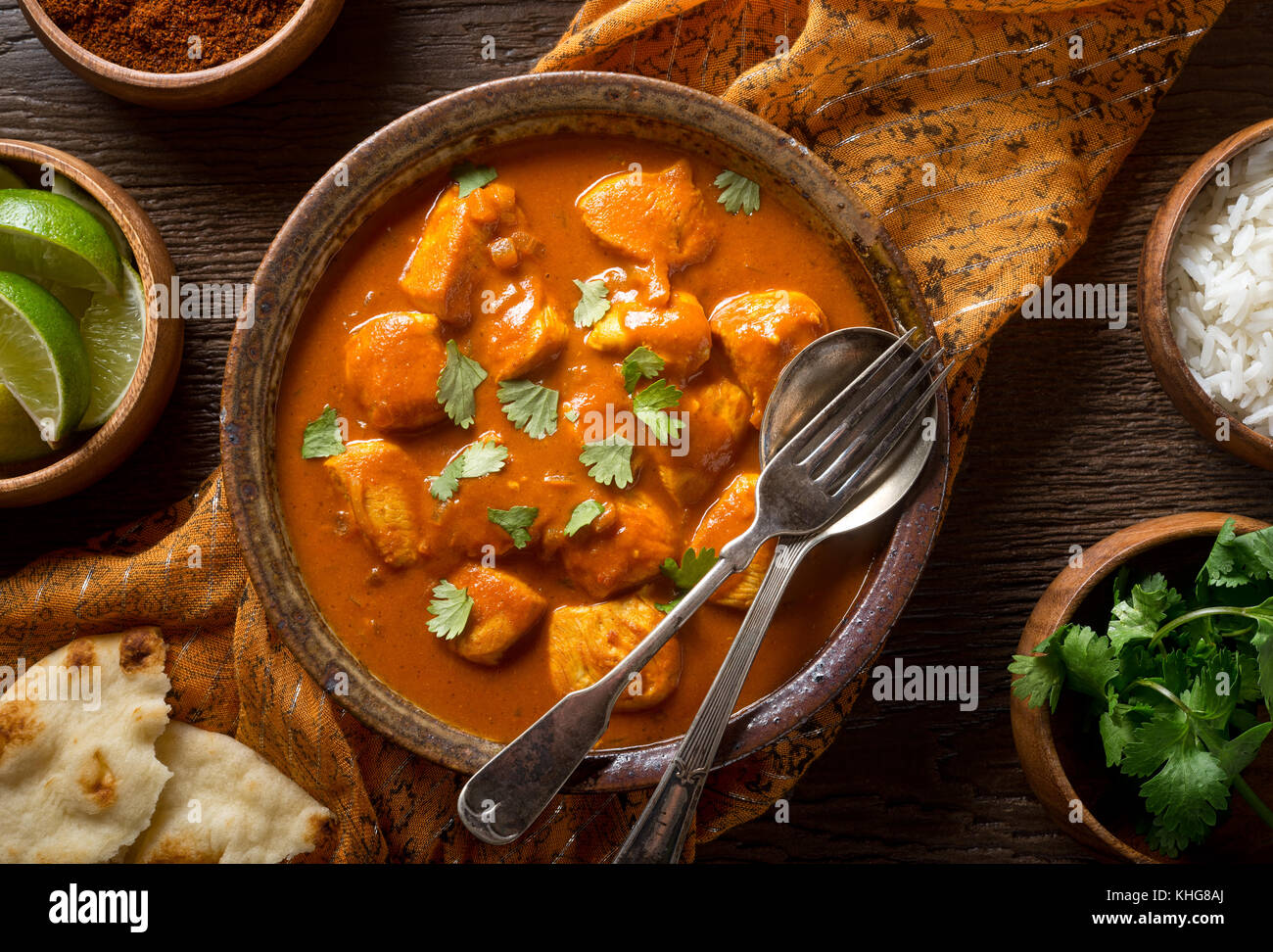 Eine Schüssel mit köstlichen indischen Butter Chicken Curry mit Naan Brot, Basmati Reis, und Koriander garnieren. Stockfoto