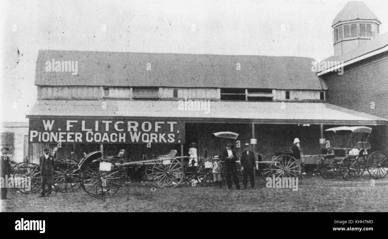 Dieses Bild zeigt eine Szene außerhalb von W. Flitcrofts Coach Works in Warwick, England, im Jahr 1904. Das Foto zeigt die Handwerkskunst und industrielle Tätigkeit im England des frühen 20. Jahrhunderts und zeigt Fahrzeuge und Werkstätten. Stockfoto