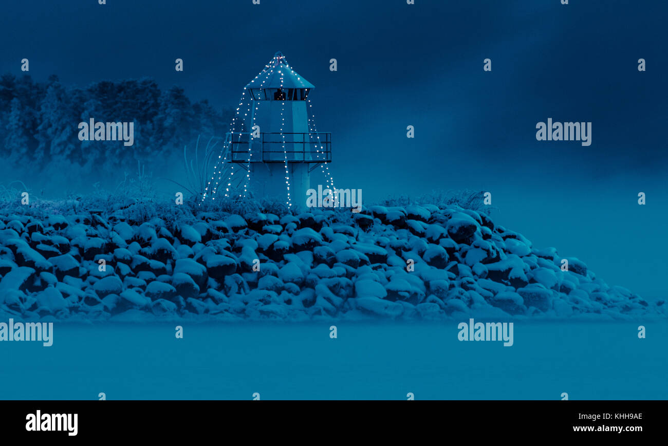 Leuchtturm am Pier mit Weihnachtsbeleuchtung. Winter Nacht und Nebel. Stockfoto