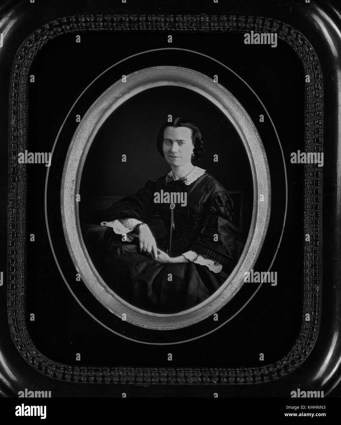 Gerahmt, oval daguerreotypie von eine Frau sitzt, trägt ein schwarzes Kleid mit langen Ärmeln und weißem Spitzenbesatz entlang des Kragens und der Unterseite der Ärmel, 1854. Von der New York Public Library. Stockfoto