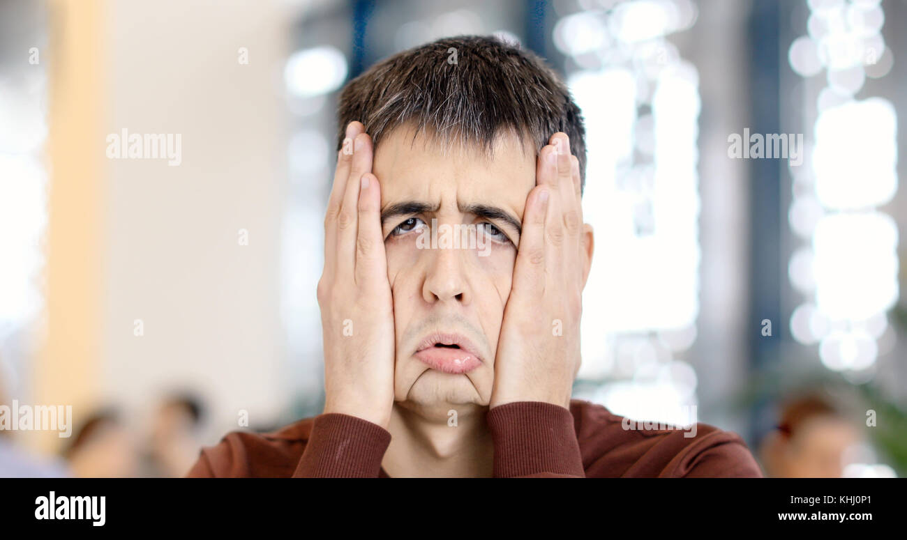 Guy schellen Gesicht mit den Händen machen ein lustiges Trauriges Gesicht Stockfoto