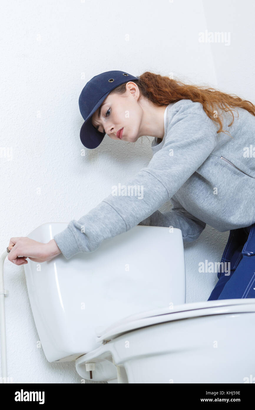 Weibliche Klempner Instandsetzung wc Zisterne, die in Wasser, Schrank Stockfoto