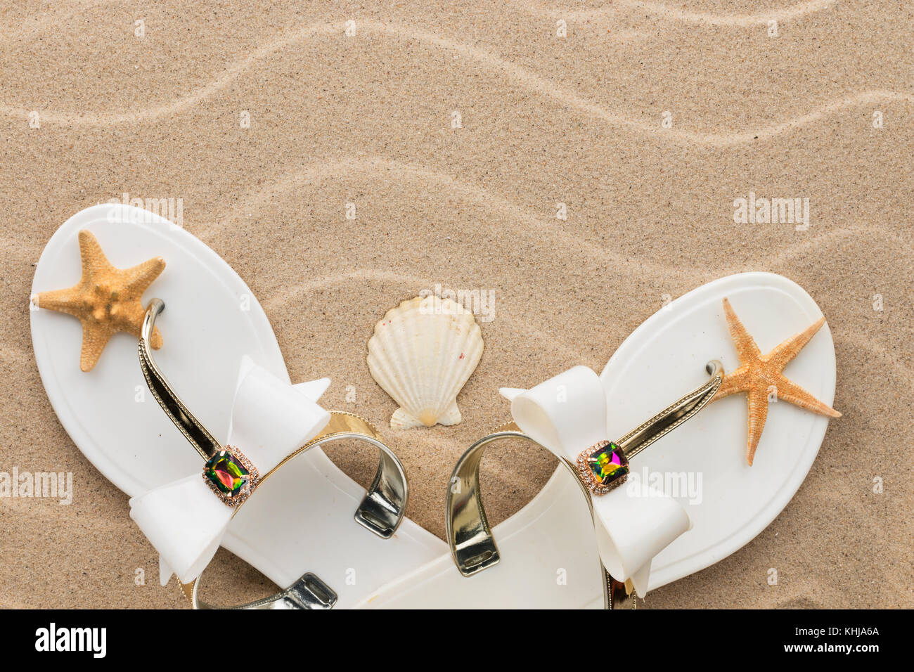 Beach Fashion, weiße Flipflops und Seesterne im Sand Strand. Mit Platz für Ihr Projekt Stockfoto