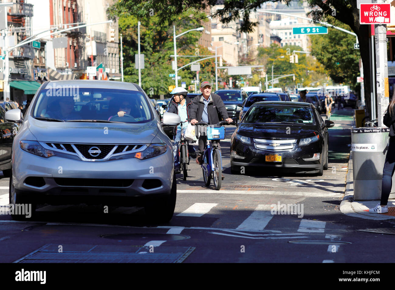 Fahrradfahrer fahren in eine Fahrspur, um ein Auto in der Mitte der Fahrradspur zu vermeiden und gleichzeitig zu vermeiden, dass ein Auto in New York City links abbiegt. Stockfoto