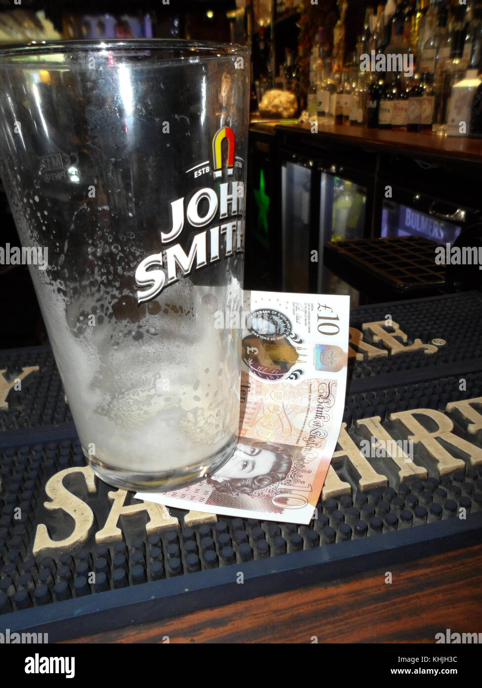 Leere pint Glas auf einem Pub Bar mit Bargeld, Sterling, für eine Nachfüllung Stockfoto