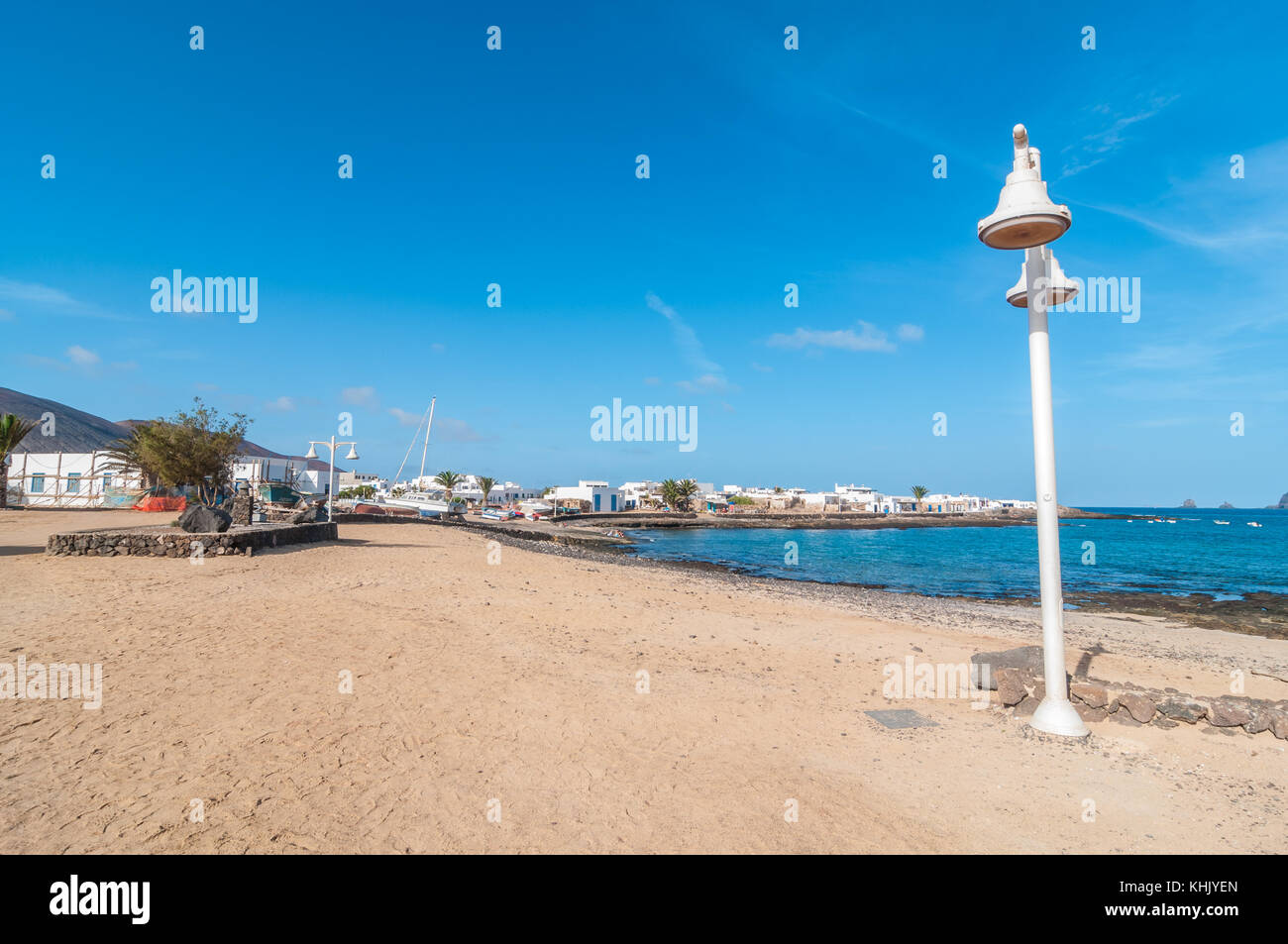 Blick auf eine typische Straße mit einem Straße Licht im Vordergrund und den Strand im Hintergrund, La Graciosa, Kanarische Inseln, Spanien Stockfoto