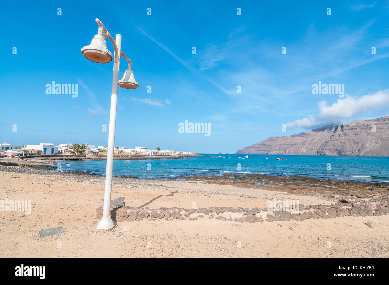 Blick auf eine typische Straße mit einem Straße Licht im Vordergrund und den Strand im Hintergrund, La Graciosa, Kanarische Inseln, Spanien Stockfoto