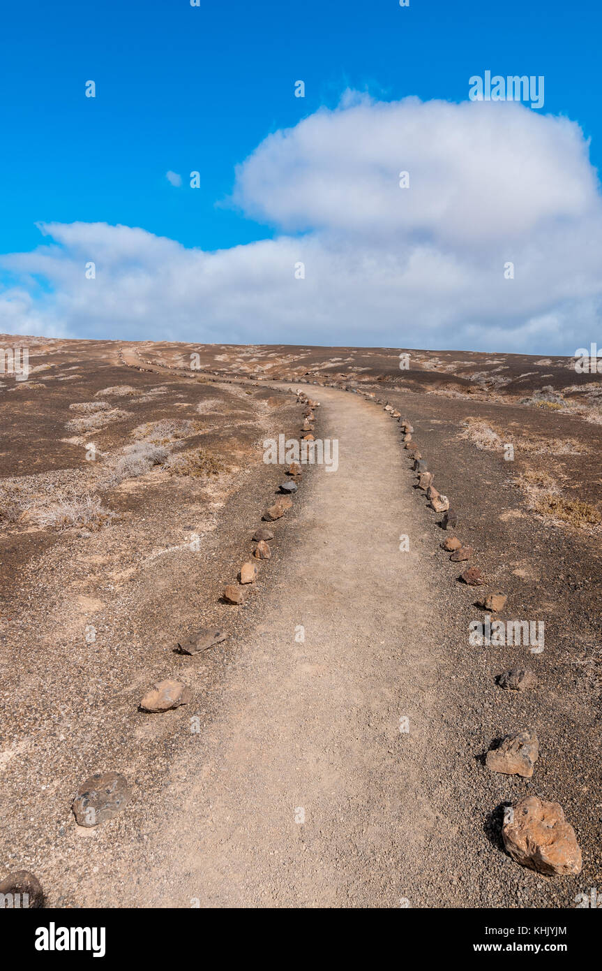 Pfad zu Montaña Bermeja mit vulkanischen Steinen an der Grenze gesetzt Markierung der Route an einem bewölkten Tag, La Graciosa, Kanarische Inseln, Spanien Stockfoto