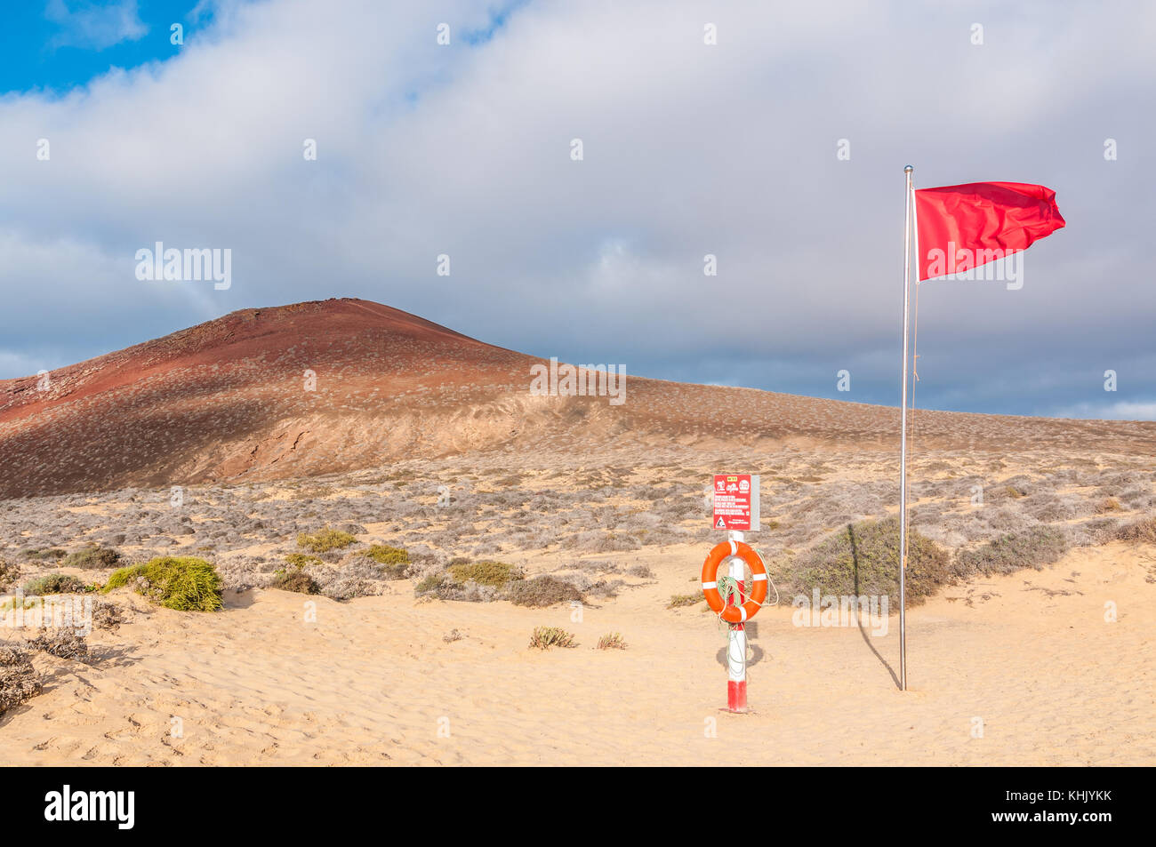 Blick auf Playa de las Conchas mit Montaña Bermeja im Hintergrund mit roten Flagge und Lebensretter im Vordergrund, La Graciosa, Kanarische Inseln, Spanien Stockfoto