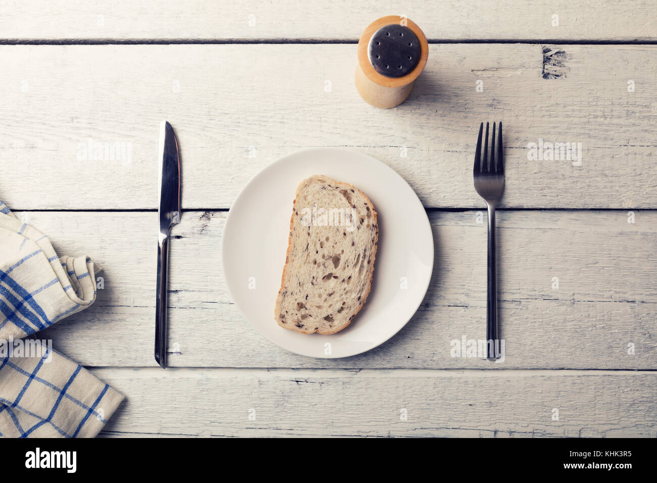 Armen Mittagessen - Scheibe Brot auf den Teller und Besteck auf hölzernen Tisch Stockfoto