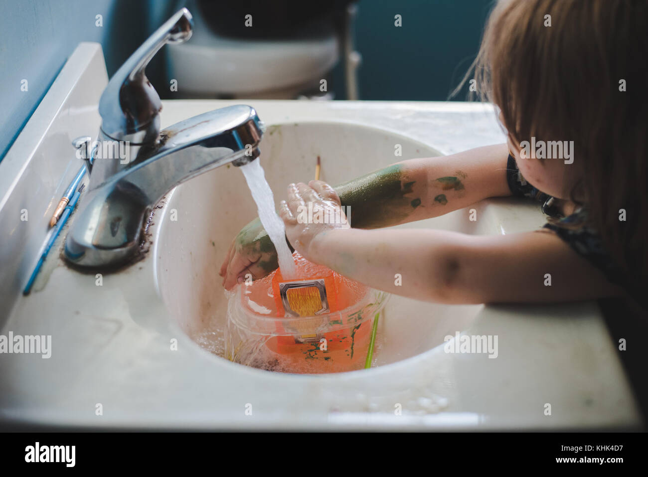 Ein Kleinkind Mädchen waschen Farbe weg die Hände in einem Waschbecken im Bad. Stockfoto