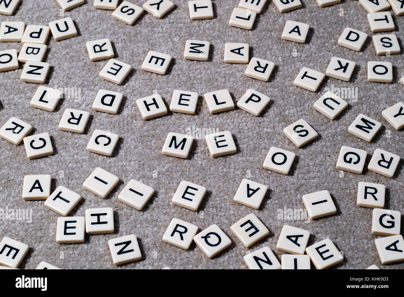 Hilf mir heraus auf scrabble Stil geschrieben beschriftete Steine unter einem Wust von anderen Buchstaben. Stockfoto