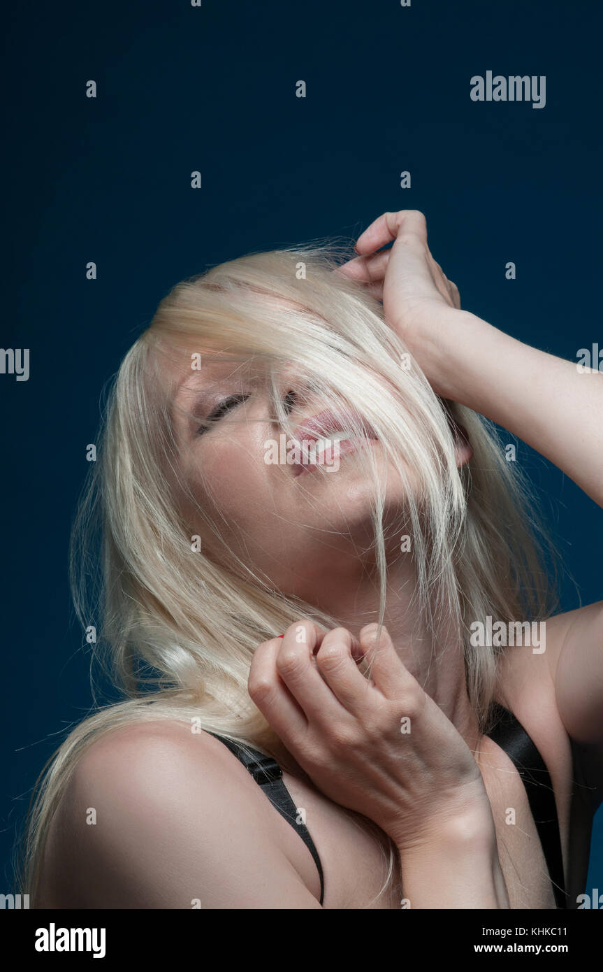 Frustrierte blonde Frauenhaare, die das Gesicht bedecken, Hände berühren den Kopf Stockfoto