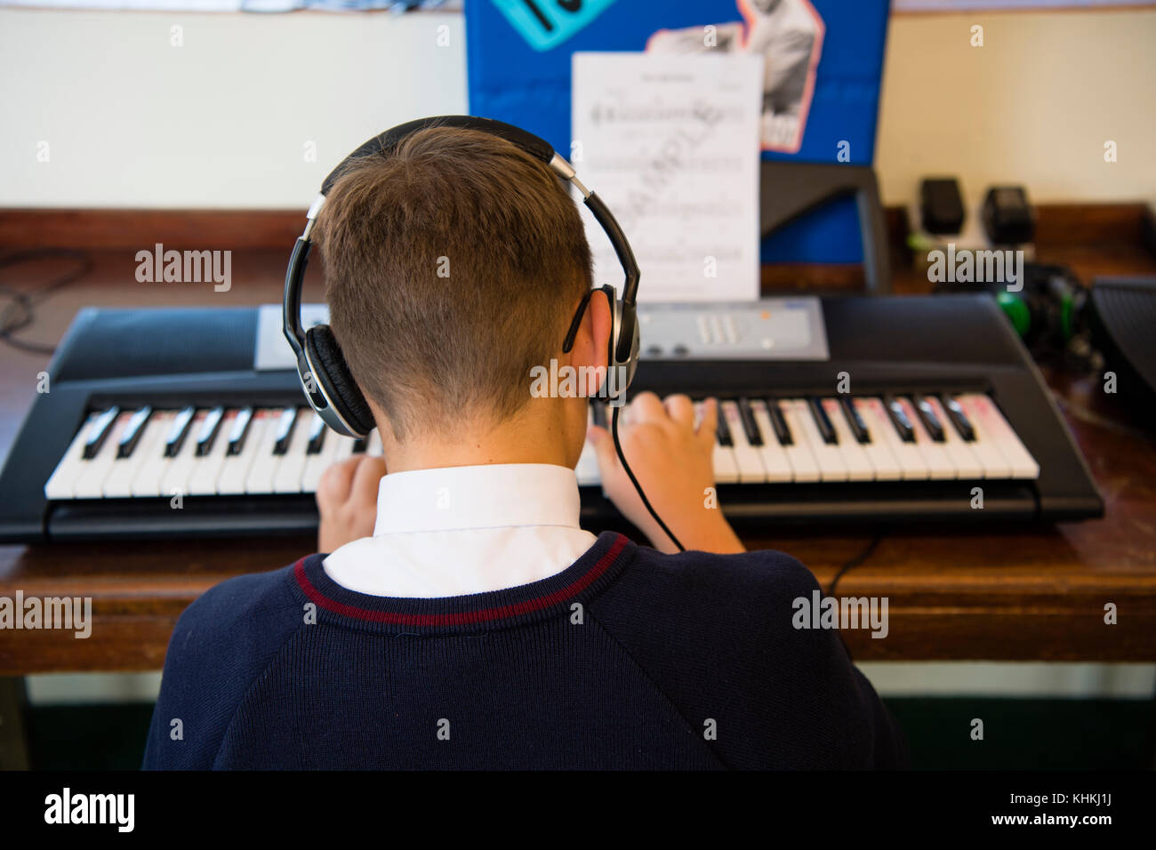 Sekundarstufe in Großbritannien: Rückansicht eines männlichen jungen Schüler mit Kopfhörern Spielen des Keyboards in eine musikstunde Klasse Stockfoto