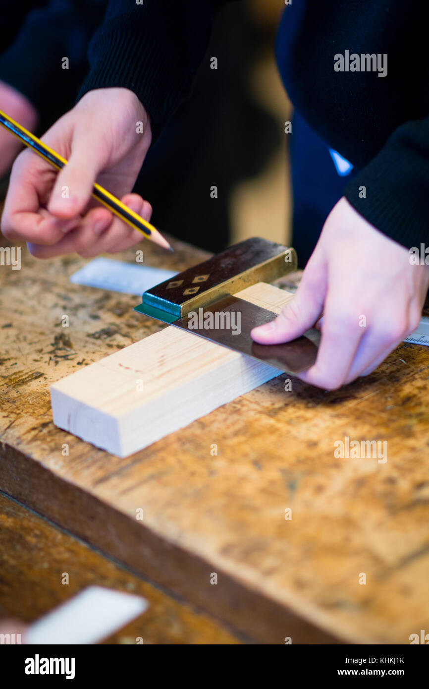 Sekundarstufe in Großbritannien: ein Schüler mit einem Satz Square die Kürzungen auf ein Stück Holz in einem HOLZARBEITEN Klasse Lektion / Design Technologie markieren Stockfoto