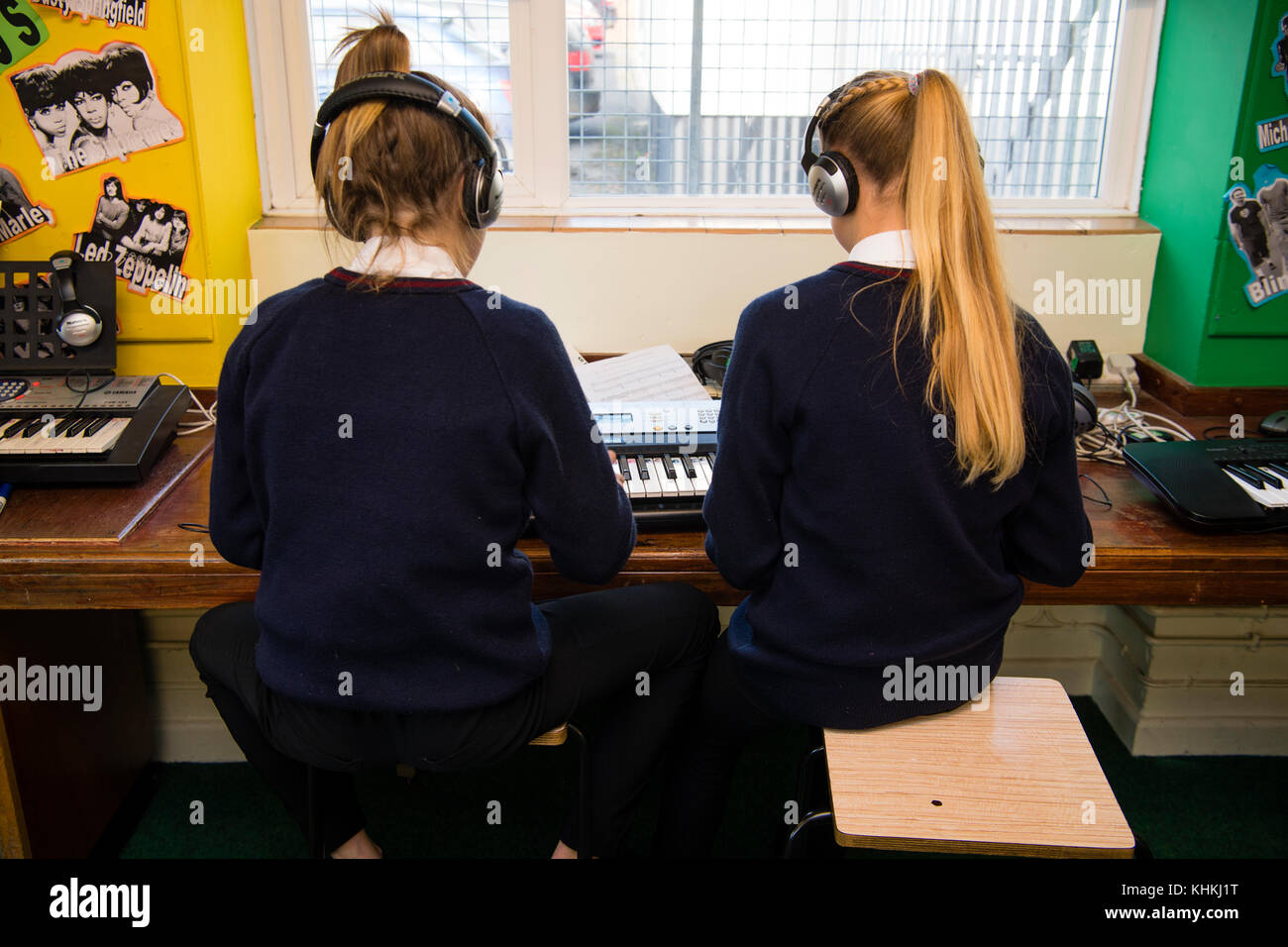 Sekundarstufe in Großbritannien: Rückansicht von zwei pubertierende Schüler mit Kopfhörern Spielen des Keyboards in eine musikstunde Klasse Stockfoto