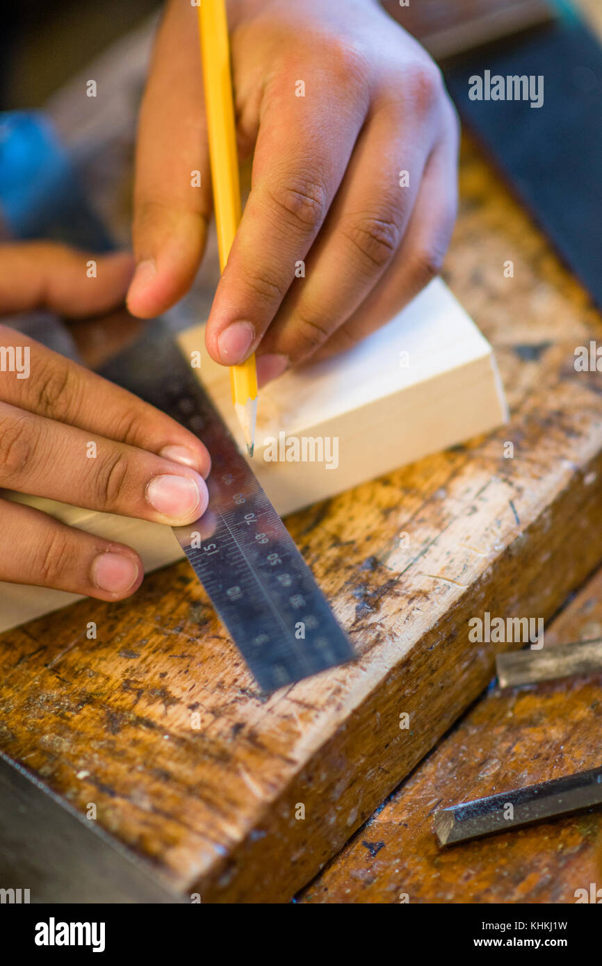 Sekundarstufe in Großbritannien: ein Schüler mit einem Satz Square die Kürzungen auf ein Stück Holz in einem HOLZARBEITEN Klasse Lektion / Design Technologie markieren Stockfoto