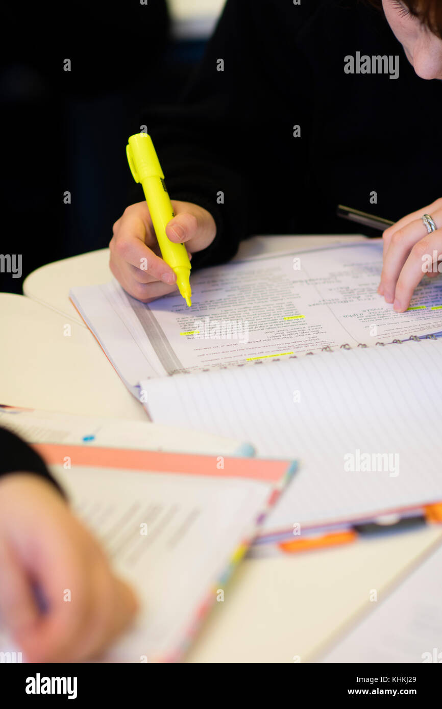Sekundarstufe in Großbritannien: Nahaufnahme der Hand eines Schülers schreiben in ihr Schulheft beachten Sie Bücher in einer Klasse Lektion Stockfoto