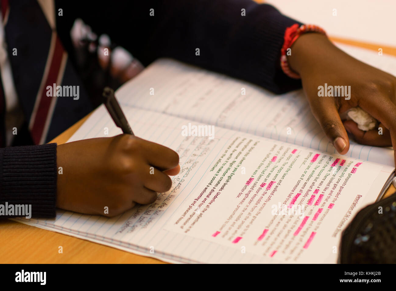 Sekundarstufe in Großbritannien: Nahaufnahme der Hand eines Schülers schreiben in ihr Schulheft beachten Sie Bücher in englischer Sprache klasse Lektion Stockfoto