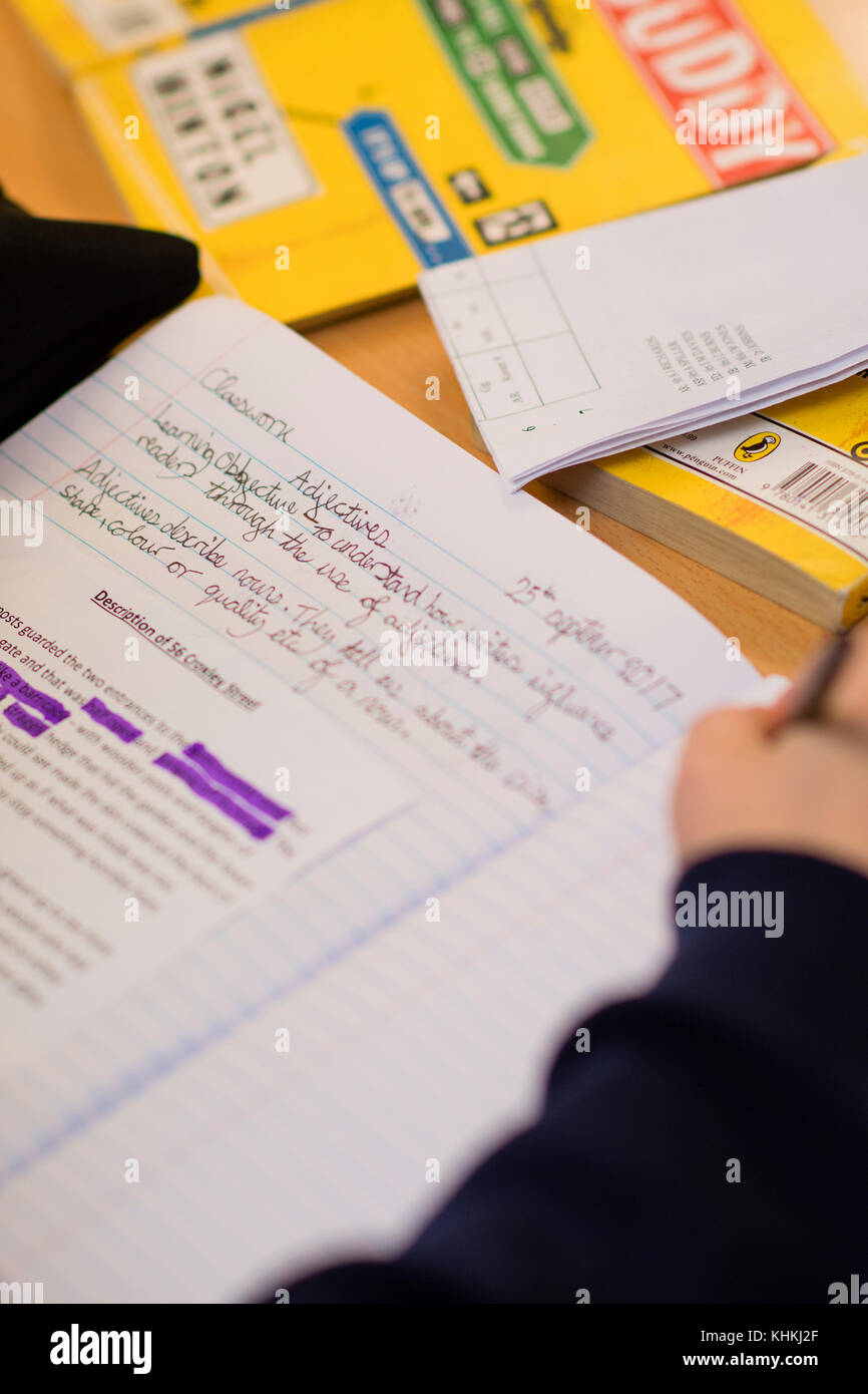Sekundarstufe in Großbritannien: Nahaufnahme der Hand eines Schülers schreiben in ihr Schulheft beachten Sie Bücher in englischer Sprache klasse Lektion Stockfoto