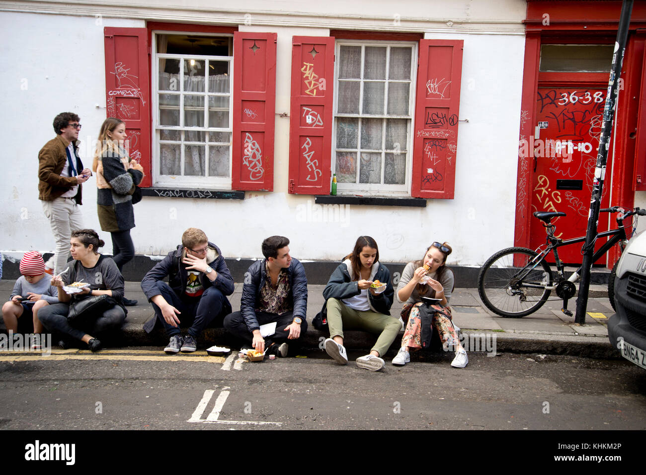 London. off Brick Lane. Besucher auf der Straße essen. Sonntag Morgen. Stockfoto