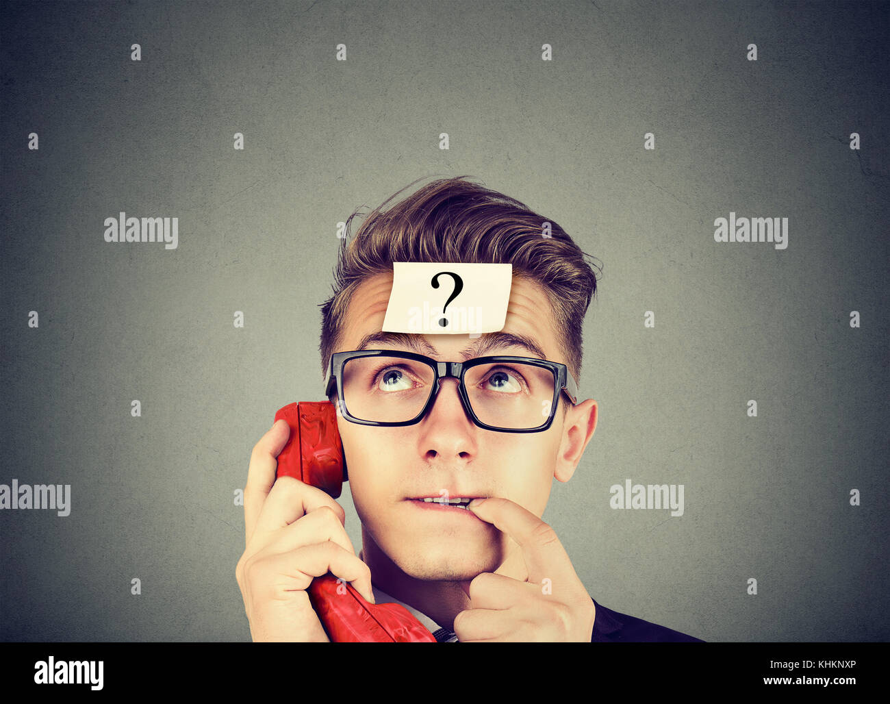 Verdutzt junger Mann mit Fragezeichen in einem Telefongespräch Stockfoto