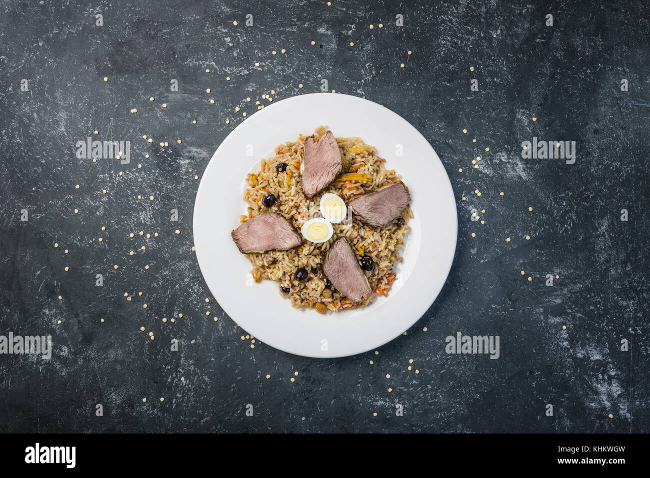 Pilav auf Platte mit orientalischen Ornament auf einem dunklen Hintergrund. zentral-asiatische Küche - Plov. Ansicht von oben. Stockfoto